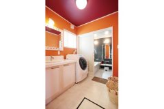 洗面所は目が覚めるようなオレンジとワインレッドの配色。5センチ角のタイルをあしらった洗面化粧台が可愛い