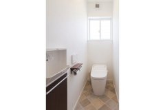 石畳を思わせるタイル調のフロアがおしゃれなトイレ。ペーパーホルダーもイメージを統一させています