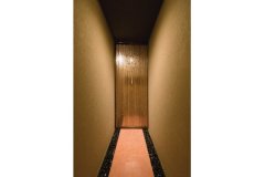 客間の和室へ向かう廊下。竹細工のドアと玉砂利の演出で茶室へのアプローチをイメージ