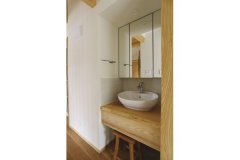 楕円形の深い洗面ボウルが可愛らしい独立洗面所。こちらも松の木の一枚板を使用して、家全体の統一感を生んでいます。