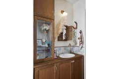 手洗い器を囲む「ミナペルホネン」のタイルや、家族の想い出の品を飾ったガラス棚で特別感のある場所に。