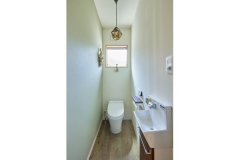 奥さまが好きな爽やかなグリーンの壁紙が空間を彩るトイレ。デザイン性の高い照明やドライフラワーが華やかに出迎えます。