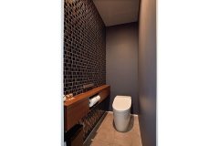 壁一面のモザイクタイルを主役にした1階トイレ。黒を基調とし、モダンで落ち着いた雰囲気に。
