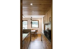 板張り天井と木目扉、側面のモルタル調の素材が調和するキッチン。背面はカフェでひと目惚れした白タイルを採用。