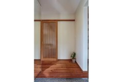 こっくりとした深い木の色みが印象的な玄関。リビングのドアは、上質なタモ材を用いてオリジナルで造作。