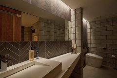 ホテルライクな女性用トイレ。幅広の洗面台にヘリンボーン柄のタイルをあしらい、おしゃれに。間接照明が上質な雰囲気を醸し出します。