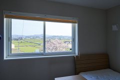 寝室からの眺めも抜群。一面に広がる緑の田園風景と、桜のピンクが美しく切り取られる。