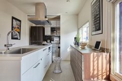 キッチンサイドの収納は、冷蔵庫を含む家電が全て収まる広さを確保。床から天井までの白いハイドアを付けたことで空間が広く見え、閉じれば壁の一部のようにすっきり。