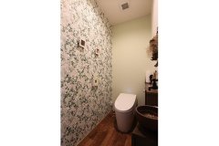 グリーンと植物柄のクロスでさわやかな印象に。アンティーク調の手洗いボウルと壁付けの水栓が遊び心を添える。