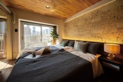 壁に天然の松島石をあしらった寝室。間仕切り上部に開口を設け、光と風を取り入れて気持ちの良い朝を迎えられるように。